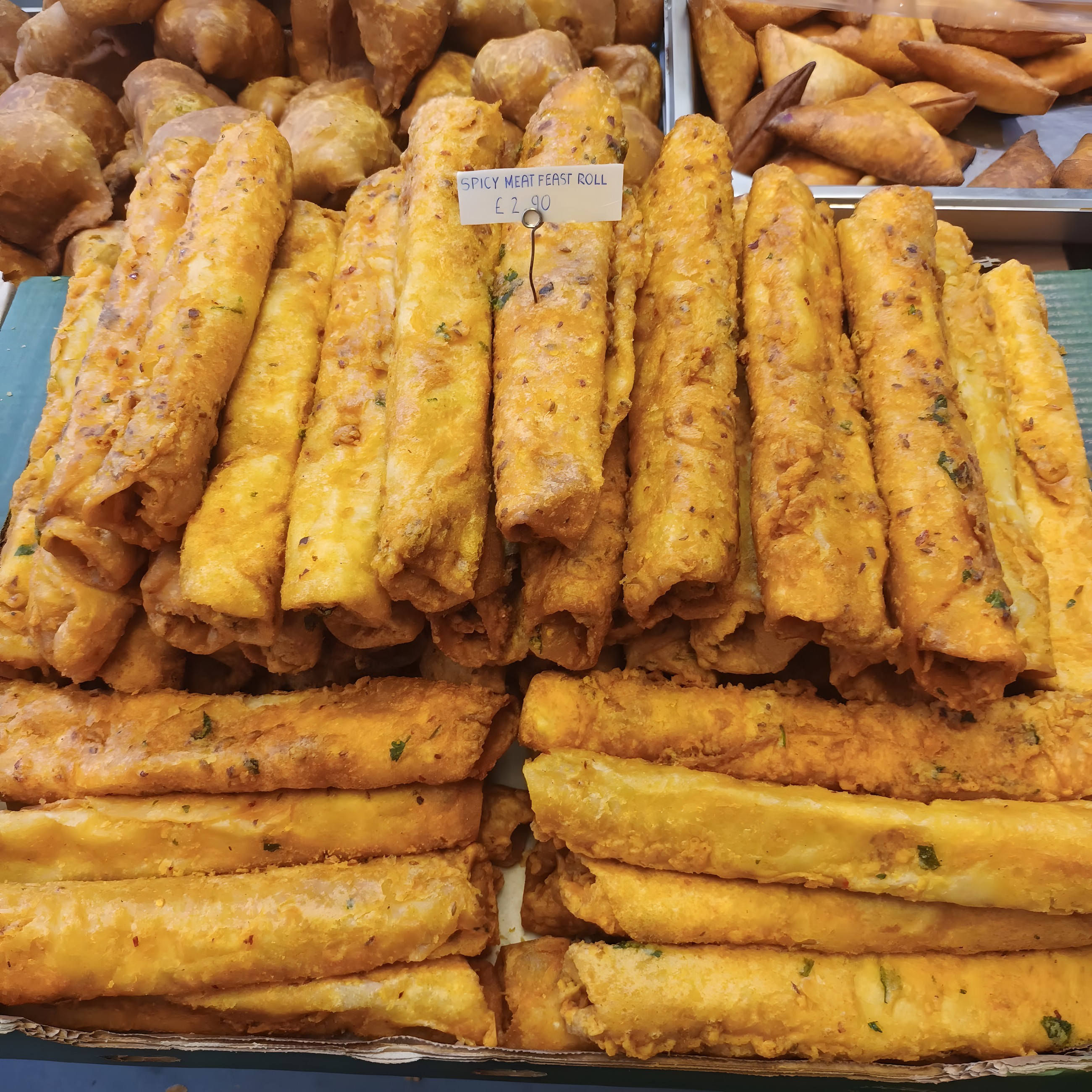 Golden fried savoury rolls stacked on the counter